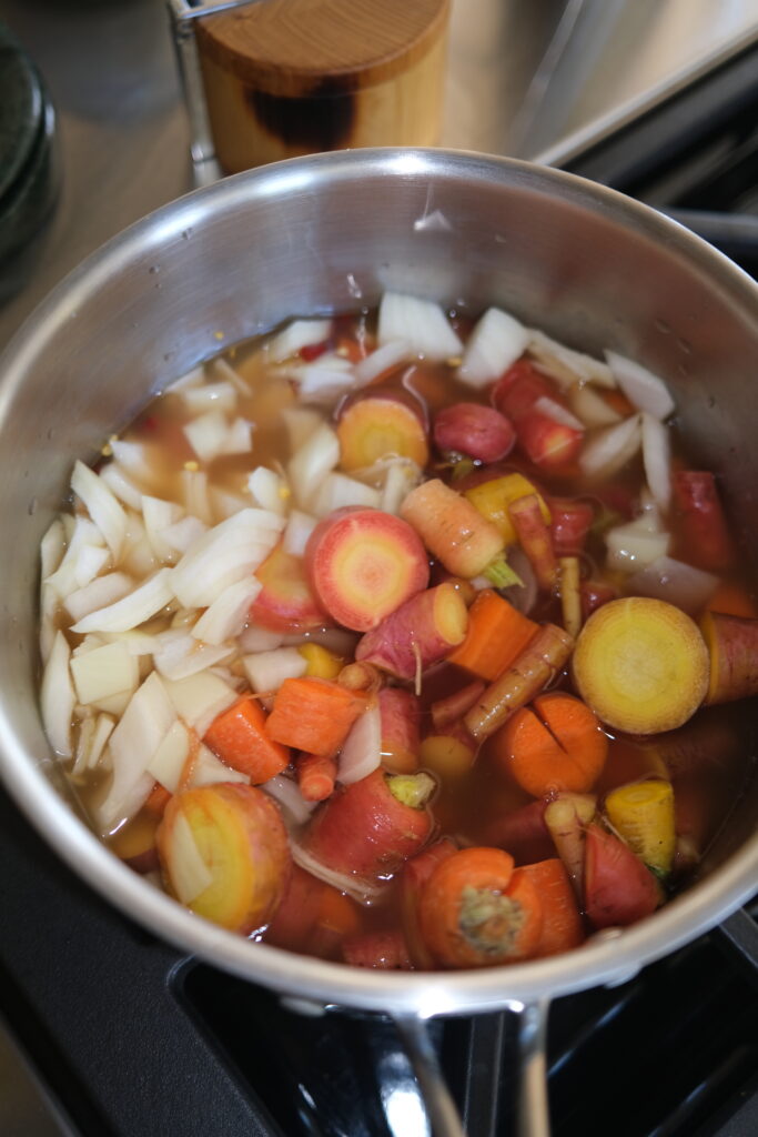 Carrots, dried cayenne peppers, garlic, and onion simmering in vinegar and water in a saucepan